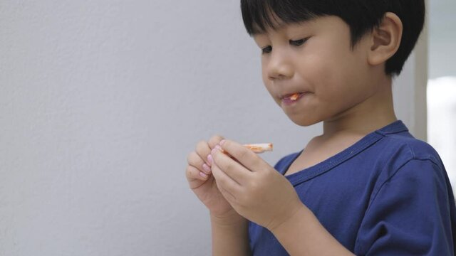 Asian boy eating crab stick. a 5 years old kid enjoy seafood product made from fish meat by his hand.