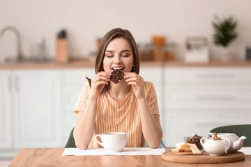 Fotobehang Beautiful young woman eating tasty chocolate at home © Pixel-Shot