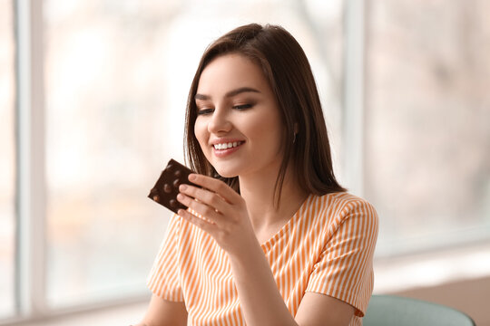 Beautiful young woman with tasty chocolate in kitchen