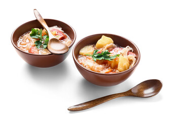 Bowls with tasty sauerkraut soup and spoons on white background