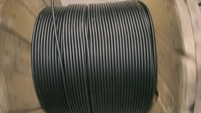 The fiber-optic cable is unwound from a wooden coil