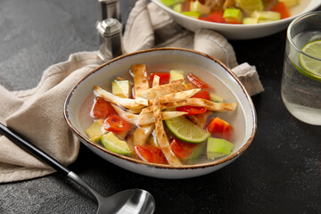 Bowl of tasty Sopa de Lima soup on dark background