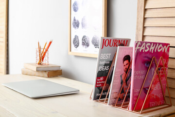 Modern workplace with magazines near light wall