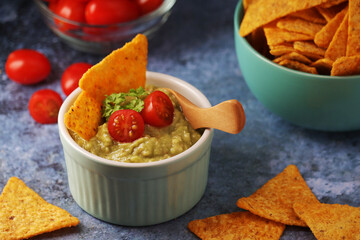 Homemade guacamole with corn chips and cherry tomatoes