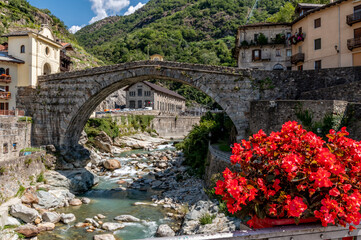 Fototapeta na wymiar Beautiful red flowers decorate the historic center of Pont Saint Martin, Valle d'Aosta, Italy, near the ancient Roman bridge