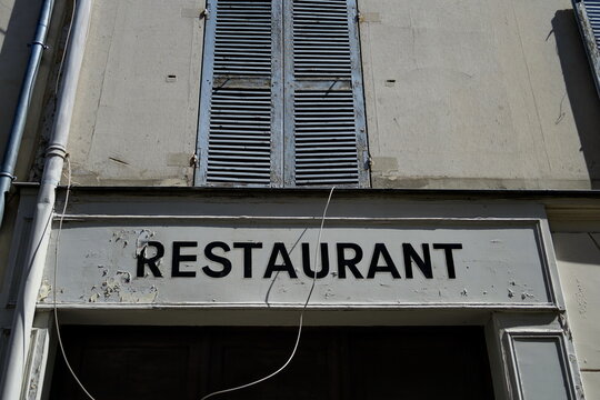 Restaurant. Enseigne sur façade ancienne avec volets fermés.