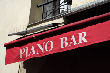 Piano Bar inscription blanche sur un store rouge.
