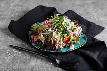Plate of fresh salad with Lollo Rosso lettuce on table