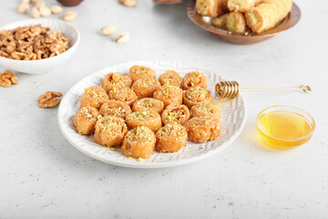 Plate with delicious baklava on light background