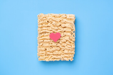 Instant noodles on blue background with red heart, fast food love concept
