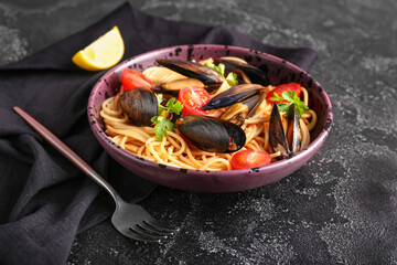 Plate of tasty Mussels Marinara with spaghetti on dark background