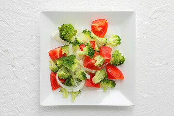 Plate of tasty salad with broccoli on light background