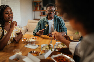 Young black friends eating take out food at home