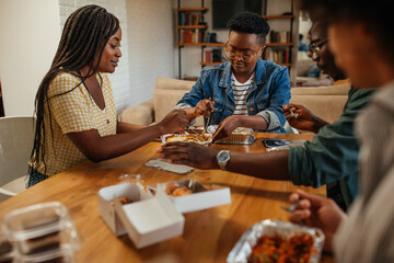 Group of young adults eating take out food at home