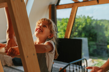 Little girl climbing wooden ladder at home