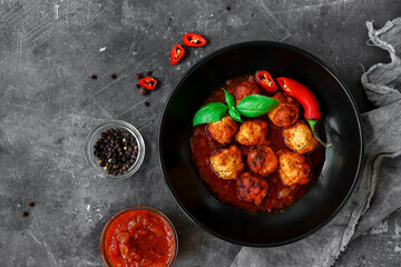 Chicken meatballs with basil and tomato sauce. Dark background. Copyspace. Meatballs with tomato and chili. Top view