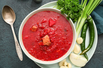 Bowl of tasty borscht and vegetables on dark background