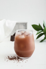 Glass of tasty chocolate milk on light background