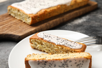 Plate with delicious glazed poppy seed cake on table