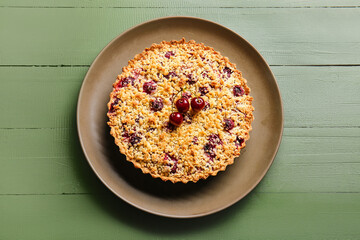 Plate with cherry pie on color wooden background