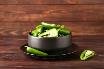 Bowl with cut green jalapeno peppers on wooden background - obrazy, fototapety, plakaty