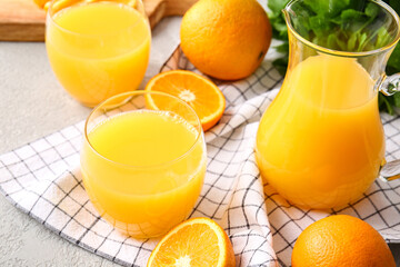 jug and glasses of tasty orange juice on light background, closeup