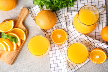 Jug and glasses of tasty orange juice on light background