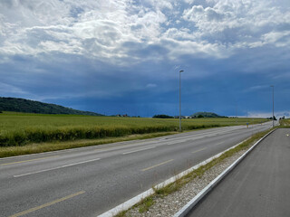 Fototapeta na wymiar Deserted road with the leaden clouds of an approaching thunderstorm on the horizon