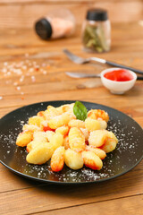 Delicious gnocchi with tomato sauce in plate on wooden table