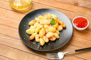 Delicious gnocchi with tomato sauce in plate on wooden table