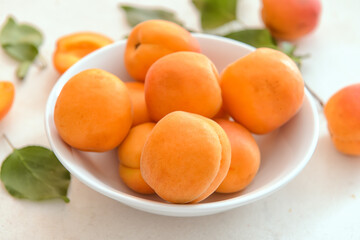 Bowl with tasty ripe apricots on light background