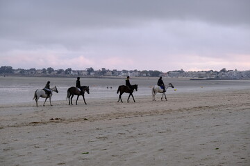 Some people riding horses on the beach of la Baule at low tide. August 2021, France.