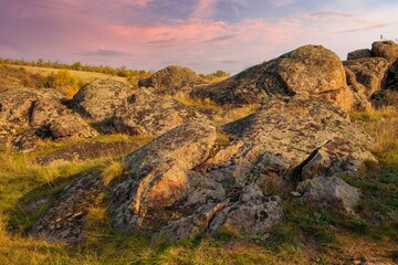 A small pile of stones in a green-yellow field against the background of a sky in Ukraine