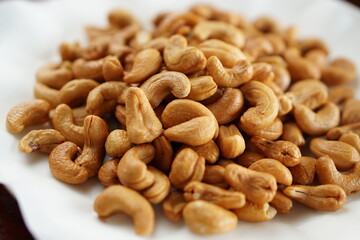 Close-up of Deep-fried cashew nuts in the fried pad and white dish on wood table.