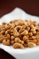 Deep-fried cashew nuts in the fried pad and white dish on wood table.