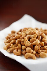 Deep-fried cashew nuts in the fried pad and white dish on wood table.