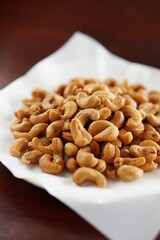 Deep-fried cashew nuts in the fried pad and white dish on wood table.
