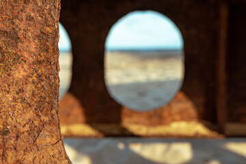 Rusty beams of the bridge located on the Baltic Sea, view of the beach on a sunny day