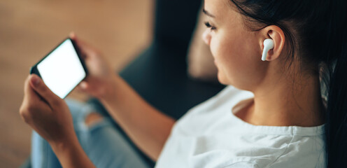 Girl in headphones holding smartphone in her hands talking on video call