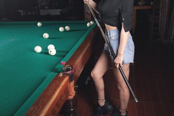 Caucasian young girl playing billiards.