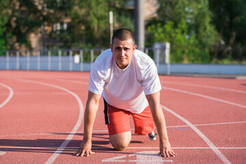 Obraz premium Caucasian male athlete with a prosthetic leg standing at the start on the track at the stadium. Sport concept.