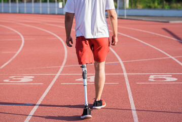 Caucasian male athlete with a prosthesis on his leg walking on the track at the stadium. Back view. Sport concept.