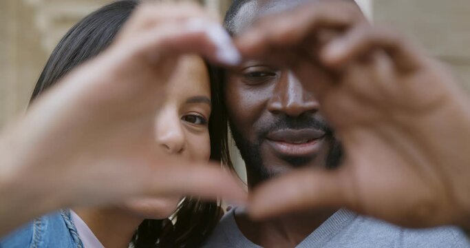 Close up african couple making heart shape with hands outdoors