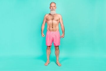 Photo of cheerful positive sportive grandpa naked torso toothy smile wear pink shorts isolated teal...