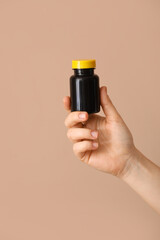 Woman holding bottle with vitamin A on color background