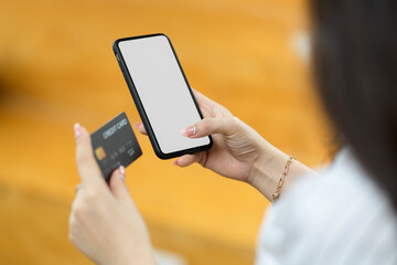 Closeup, female holding credit card and smartphone mockup, blurred background