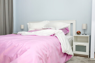 Bed in the hotel covered with pink linens