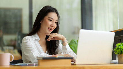 Attractive business female boss working on laptop computer in office