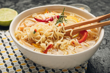 Bowl of tasty Thai soup on dark background, closeup