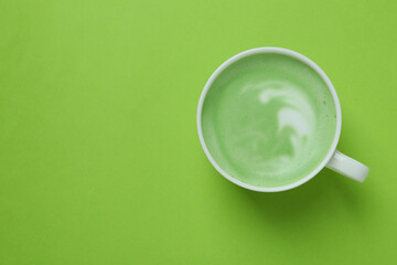 Cup of matcha latte on green background